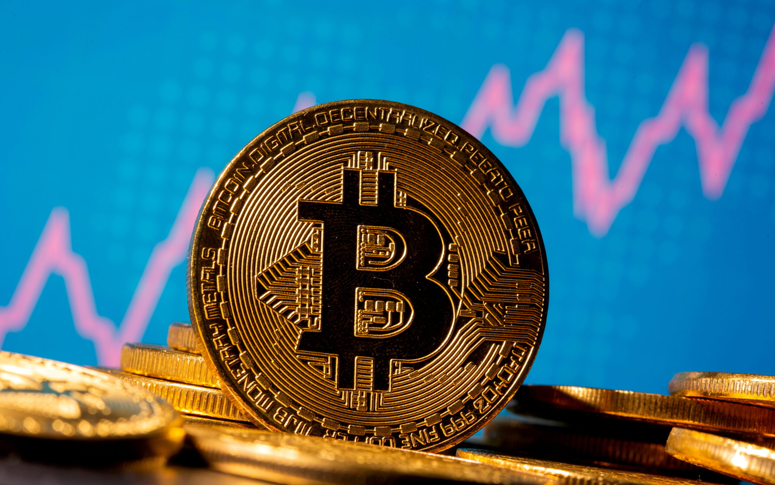 FILE PHOTO: A representation of virtual currency bitcoin is seen in front of a stock graph